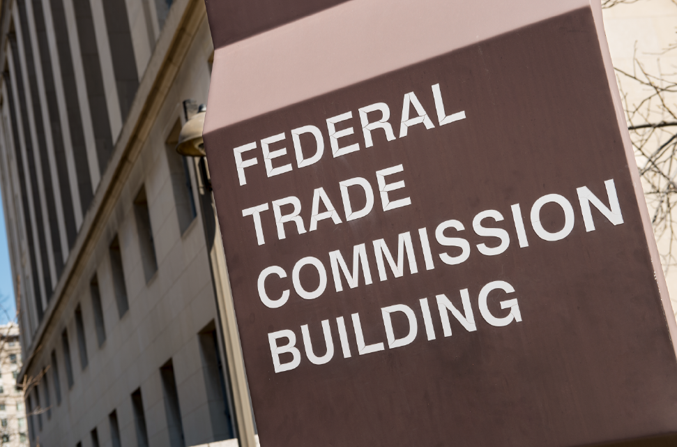 Sign for the federal trade commission building with modern buildings in the background on a sunny day.